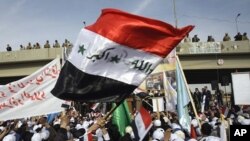 به‌رزکردنه‌وه‌ی ئاڵای سه‌رده‌می سه‌دام حسێن له‌ خۆپـیشـاندانێـکدا له‌ شـارۆچکه‌ی فه‌لـلوجه‌ی سووننه‌ نشین له‌ ڕۆژئاوای به‌غدا، 14 ی دوازده‌ی 2011