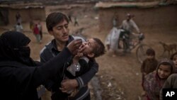 Seorang pekerja medis Pakistan (kiri) memberikan vaksin polio kepada seorang anak di sebuah perkampungan kumuh di Islamabad. (Foto: Dok)