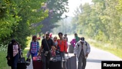 Twa fanmi ki di yo soti Burundi kap mache sou wout Roxham a nan direksyon fwontyè Etazini-Kanada nan zòn Champlain, New York, 3 out 2017. Foto: Reuters / Christinne Muschi. 90 pousan imigran kap kouri antre Kanada yo se ayisyen. 