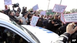 A striking municipal police officer reacts as he leans on a car with a Greek flag during a protest, against new austerity cuts that will affect thousands of public sector workers, in Athens. The government has committed to firing 15,000 people by the end of 2014 and transferring another 12,500 to new positions this year.