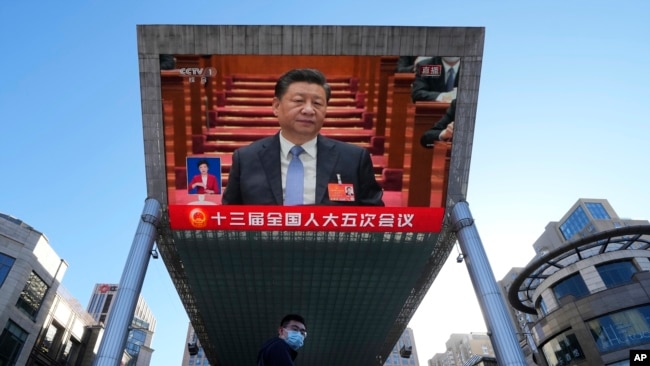 Chinese President Xi Jinping is seen on a live broadcast of the opening ceremony for the National People's Congress at a mall on March 5, 2022, in Beijing