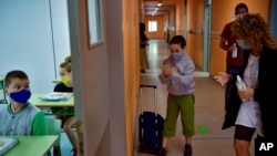 A young student wearing a face mask to prevent the spread of the coronavirus disinfects his hands before entering a classroom, at the Labastida Ikastola school, in the small basque town of Labastida, northern Spain, Sept. 8, 2020. 