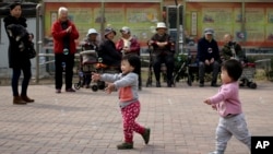 FILE - In this March 31, 2016, file photo, children play bubbles at a residential compound in Beijing. 