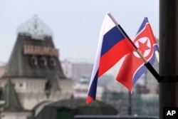 Bendera Rusia dan Korea Utara terlihat di depan stasiun kereta api pusat di Vladivostok, Rusia, Rabu, 24 April 2019. (Foto: via AP)
