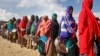 FILE - Newly-arrived women who fled drought queue to receive food distributed by local volunteers at a camp for displaced persons in the Daynile neighborhood on the outskirts of the capital Mogadishu, in Somalia, May 18, 2019. 