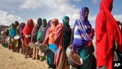 FILE - Newly-arrived women who fled drought queue to receive food distributed by local volunteers at a camp for displaced persons in the Daynile neighborhood on the outskirts of the capital Mogadishu, in Somalia, May 18, 2019. 