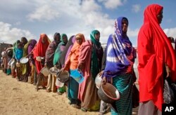 FILE - Newly-arrived women who fled drought queue to receive food distributed by local volunteers at a camp for displaced persons in the Daynile neighborhood on the outskirts of the capital Mogadishu, in Somalia, May 18, 2019.