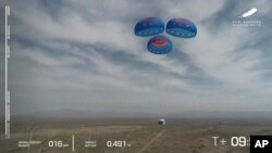 In this image from video made available by Blue Origin, the New Shepard capsule uses parachutes to land during a test in West Texas on Wednesday, April 14, 2021. (Blue Origin via AP)