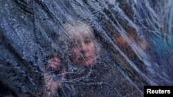 Raindrops are seen on outdoor protective plastic sheeting surrounding a woman on her phone at a cafe in Galway, Ireland, October 20, 2020.