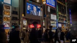 18일 일본 도쿄 신주쿠 거리에 설치된 대형 TV에서 스가 요시히데 총리의 기자회견 소식이 나오고 있다.