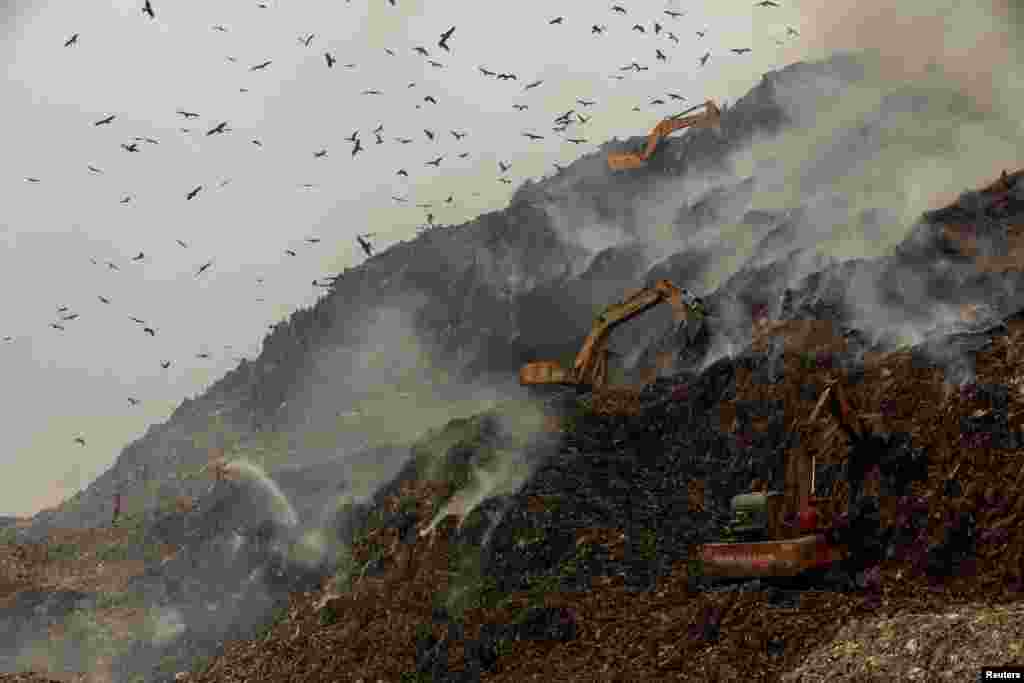 Firefighters and excavators douse fire as smoke billows from burning garbage at the Ghazipur landfill site in New Delhi, India.