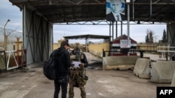 FILE - A Russian soldier inspects a petition from a Syrian man at the entrance of the Russian-leased Syrian military base of Hmeimim in Latakia province in western Syria on Dec. 29, 2024. 