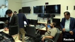 An official for RTUK, left, takes notes in the master control room of IMC TV in Istanbul, Turkey, Oct. 4, 2016.