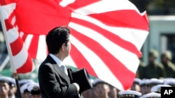 FILE - Japanese Prime Minister Shinzo Abe reviews members of Japan Self-Defense Forces (SDF) during the Self-Defense Forces Day at Asaka Base, north of Tokyo, Sunday, Oct. 27, 2013.