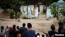 Warga berdiri di depan daerah yang digenangi banjir di Kampung Sewu di Solo, Jawa Tengah (19/6). 