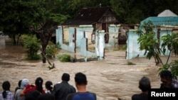 People stand in front of a flooded area in Kampung Sewuresidential area in Solo, Central Java province, Indonesia, June 19, 2016.