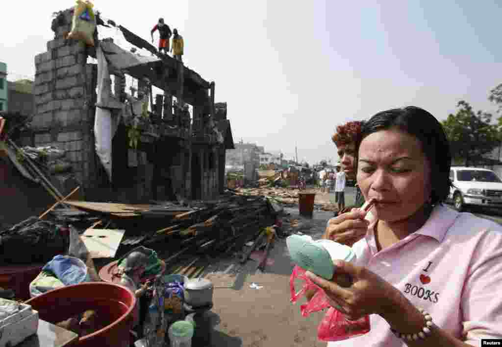A woman applies lipstick while her family's concrete house is being demolished in a squatter colony in Tondo, Manila.