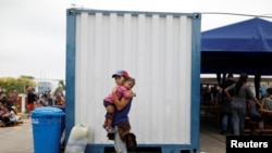 Una joven venezolana espera con su hija en brazos la documentación en la frontera entre Perú y Ecuador para pasar a ese primer país como refugiada.