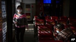 Travelers wear face masks as they wait for trains the Beijing Railway Station in Beijing, Jan. 31, 2020. 