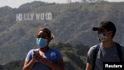 People wearing face masks walk past the Hollywood sign in the distance, after a partial reopening of Los Angeles hiking trails during the outbreak of the coronavirus disease (COVID-19) at Griffith Park in Los Angeles, California, U.S., May 9, 2020. REUTER