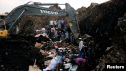 Une excavatrice creuse dans une montagne de déchets en présence de secouristes à la recherche de personnes disparues après l'éboulement de la décharge de Koshe, à Addis Ababa, le 13 mars 2017.