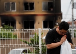 A man prays for victims in front of the torched Kyoto Animation building in Kyoto