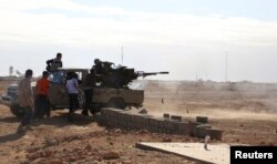 FILE - Fighters are seen firing a vehicle-mounted weapon on the outskirts of Sidra, Libya. Libya's political crisis has persisted since the overthrow of former leader Moammar Gadhafi.