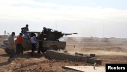 FILE - Fighters are seen firing a vehicle-mounted weapon on the outskirts of Sidra, Libya. The report describes unlawful killings, including executions of people taken captive. 