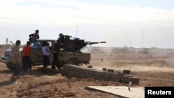 FILE - Fighters are seen firing a vehicle-mounted weapon on the outskirts of Sidra, Libya, Dec. 14, 2014.