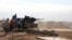 FILE - Fighters are seen firing a vehicle-mounted weapon on the outskirts of Sidra, Libya. The report describes unlawful killings, including executions of people taken captive. 