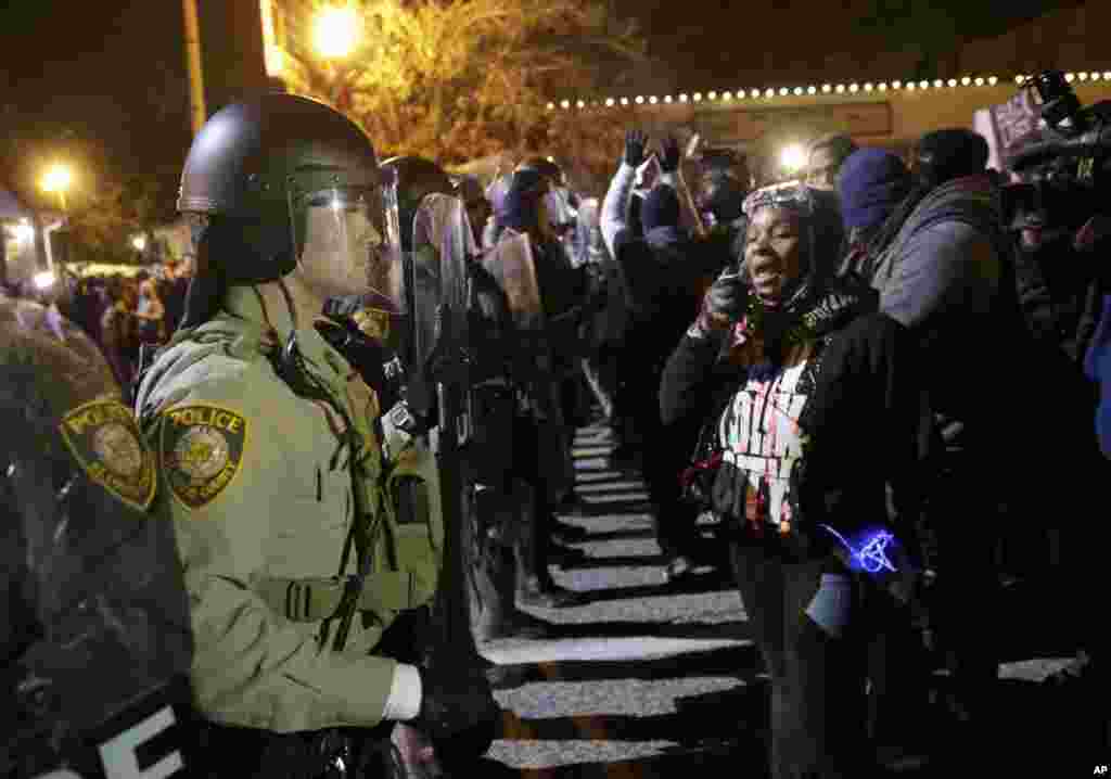 Petugas polisi berjaga-jaga sementara para demonstran memprotes pengumuman keputusan dewan juri untuk tidak menuntut polisi Darren Wilson tentang penembakan fatal Michael Brown, di Ferguson, Missouri, 24 November 2014.