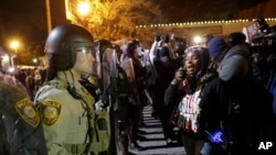 FILE - Police stand guard as protesters react to the announcement of the grand jury decision not to indict Officer Darren Wilson in the fatal shooting of Michael Brown, an unarmed black 18-year-old, Nov. 24, 2014, in Ferguson, Mo. 