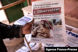 A man buys a newspaper with the picture of Paul-Henri Sandaogo Damiba, the leader of the mutiny and of the Patriotic Movement for the Protection and the Restauration (MPSR), in Ouagadougou, Burkina Faso, Jan. 25, 2022.