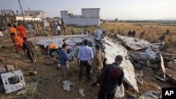 Paramilitary soldiers and members of the media gather near the wreckage of a Boeing 737 airliner that crashed in Islamabad, April 21, 2012. 