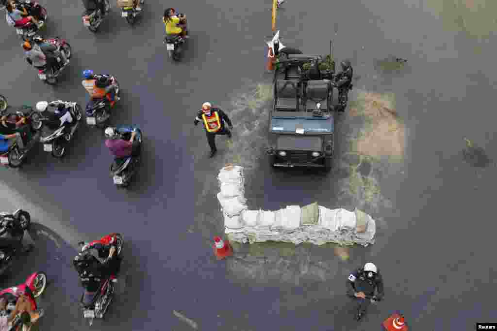 Commuters drive their motorcycles past Thai soldiers positioned in the middle of a main intersection in the shopping district, in Bangkok, May 20, 2014.