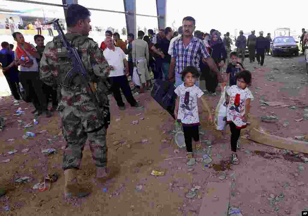 Polisi Kurdi berjaga-jaga sementara para pengungsi dari Mosul mengarah ke wilayah otonom Kurdi di Irbil, Irak, 350 kilometer dari Baghdad (10/6).&nbsp;