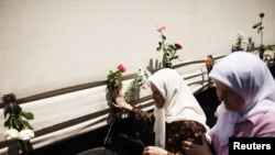 Bosnian women touches one of three trucks carrying 520 coffins of newly identified victims of Srebrenica massacre