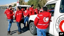 Staff from the Syrian Arab Red Crescent get ready to accompany a convoy of humanitarian aid as it waits in front of the United Nations Relief and Works Agency (UNRWA) offices before making their way into the government besieged rebel-held towns of Madaya, Zabadani and Moadimayet al-Sham in the Damascus countryside, as part of a U.N.-sponsored aid operation, in Damascus, Syria, Feb. 17, 2016.