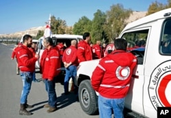 Staff from the Syrian Arab Red Crescent get ready to accompany a convoy of humanitarian aid as it waits in front of the United Nations Relief and Works Agency (UNRWA) offices before making their way into the government besieged rebel-held town of Madaya.