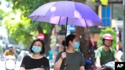 Women wearing face masks walk on the street in Hanoi, July 30, 2020 as Vietnam reported several more cases of COVID-19, the first outbreak in over three months spread to cities while authorities say they cannot trace its source.