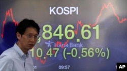 A currency trader walks by a screen showing the Korea Composite Stock Price Index at the foreign exchange dealing room in Seoul, South Korea, April 16, 2020. 