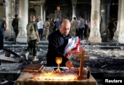 FILE - An Iraqi Christian prepares for the first Sunday mass at the Grand Immaculate Church since it was recaptured from Islamic State in Qaraqosh, near Mosul in Iraq, Oct. 30, 2016.