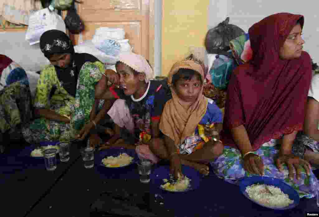 Migrants believed to be Rohingya take their breakfast inside a shelter after being rescued from boats at Lhoksukon, in Indonesia's Aceh Province.