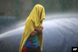 An unidentified player of Afghanistan cricket team covers himself with a towel as he runs for shelter during sudden rains at a training session ahead of one-off test match against India in Bangalore, India, June 13, 2018.