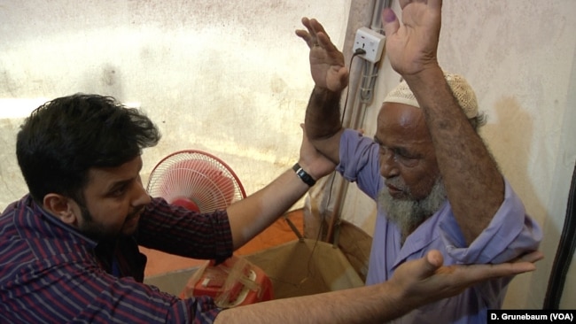 Dr. Shaikot Majumder examines Abdu Zabber, who says he feels pain across his body.