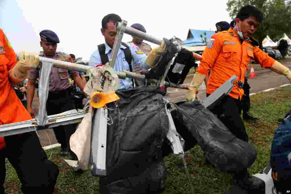 National Search and Rescue Agency personnel carry the seats of AirAsia Flight 8501 after being airlifted by a U.S. Navy helicopter at the airport in Pangkalan Bun, Indonesia, Jan. 5, 2015.