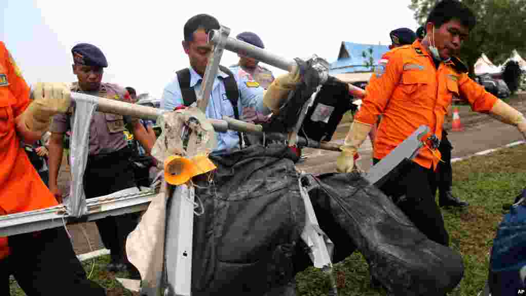 Des travailleurs de l'Agence national de recherche et de sauvetage portent des sièges de l'avion d'AirAsie, Vol 8501, après avoir été transporté par un hélicoptère de la marine américaine à l'aéroport de Pangkalan Bun, l'Indonésie, le 5 janvier 2015.