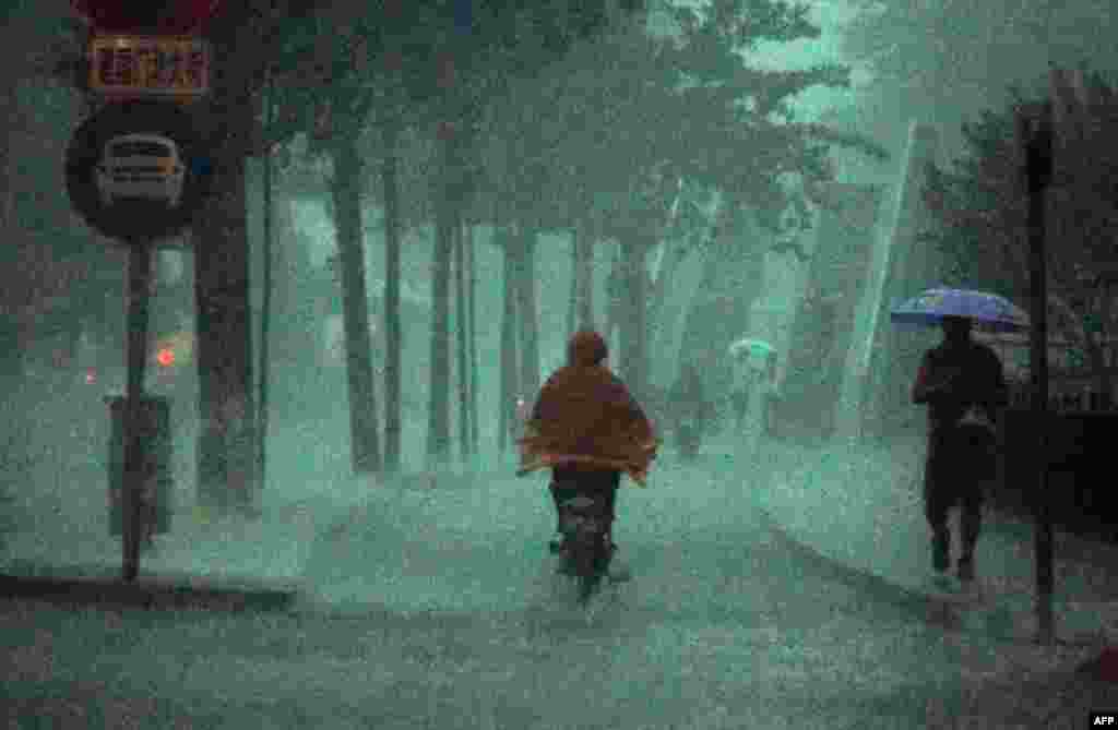 June 23: A man rides his bike during a heavy rain storm in Beijing. Torrential rains in central and southern China threaten the Yangtze River basin and nearby provinces with deadly floods and mudslides. (REUTERS/David Gray)