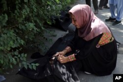 An Afghan woman tries to identify a body at a hospital in Kabul, Afghanistan, Aug. 27, 2021, a day after a deadly attack outside the airport.