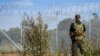 A guard stands at the border fence with barbed wire during a press tour to present military reinforcement measures at the border of Latvia with Russia, on August 16, 2024 near Karsava, Latvia.